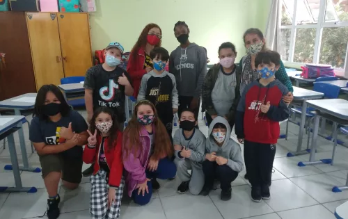 alunos imigrantes segurando uma bandeira do Haiti em sala de aula em projeto "Abraços Abertos" da EEB Professora Maria Amin Ghanem, de Joinville