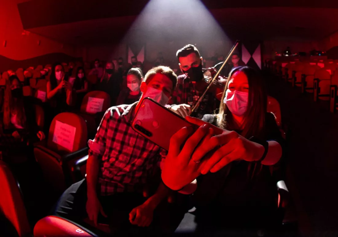 Estudante em teatro tirando selfie com violinista 
