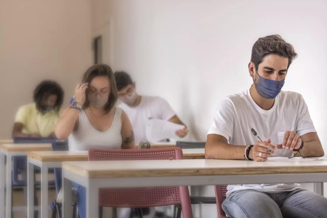 estudantes utilizando máscara facial descartável em sala de aula fazendo vestibular 