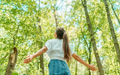Garota de braços abertos em floresta na natureza