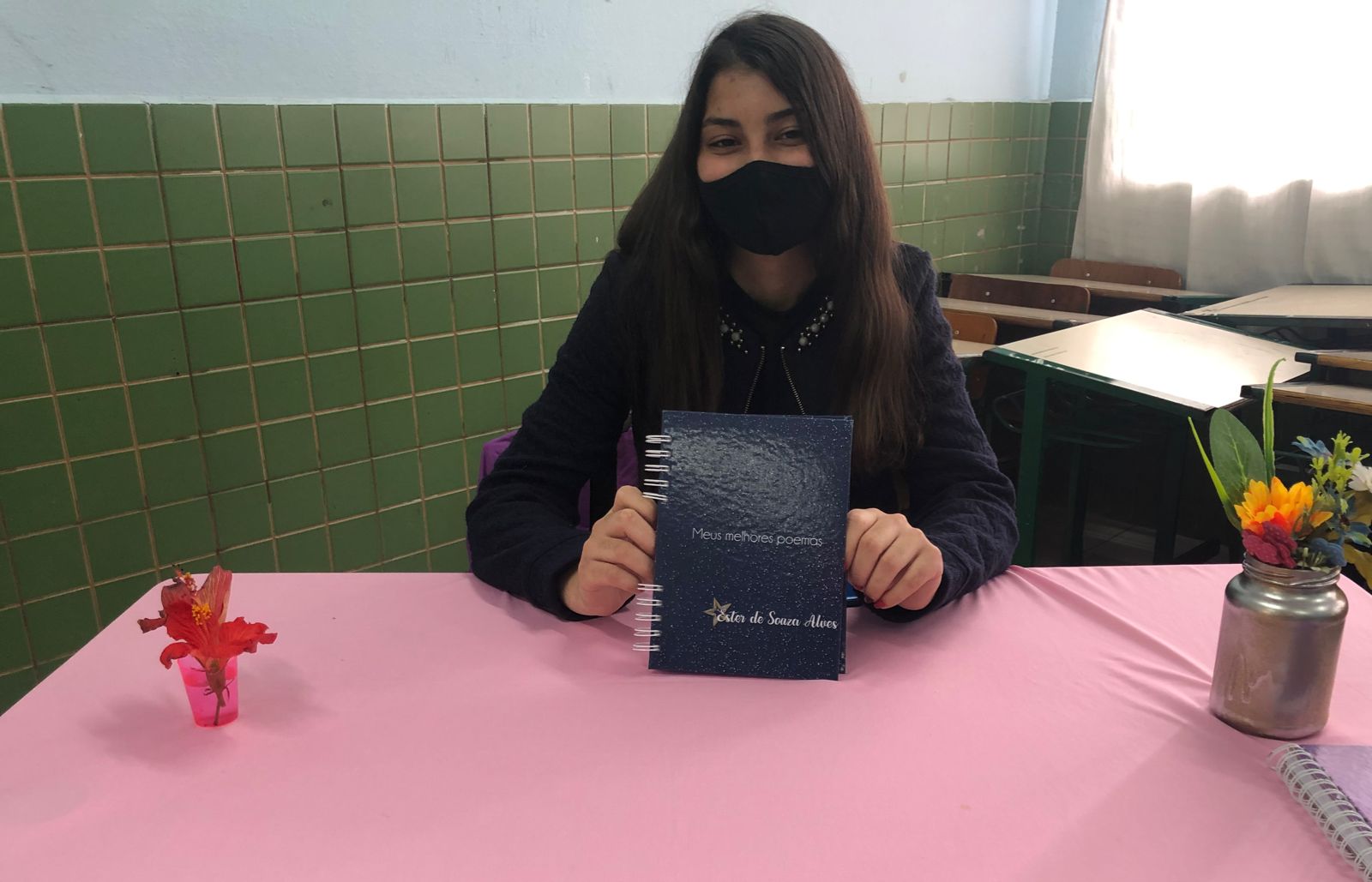 Ester de Souza segurando livro na exposição do projeto "Escritores da GAM"