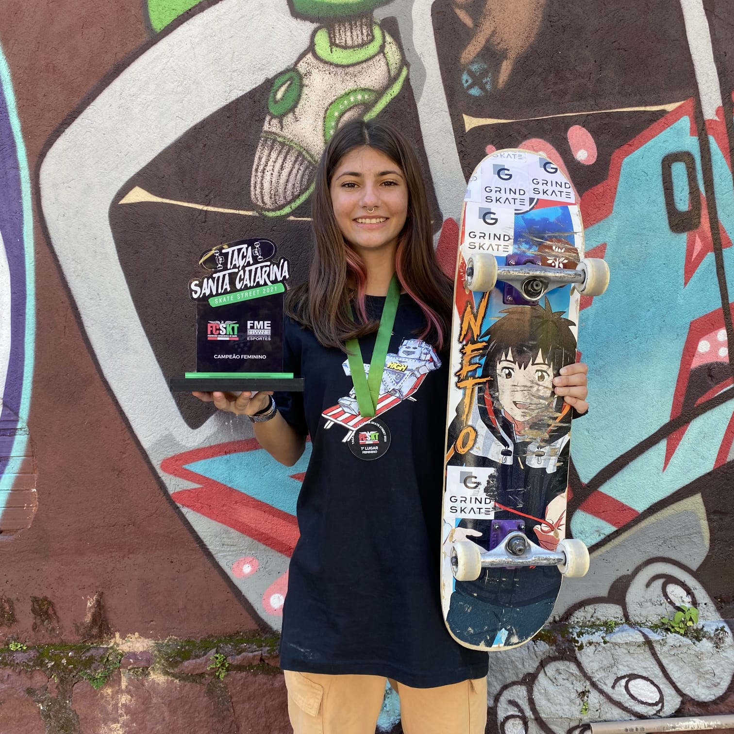 Estudante Giovana Gabriela Roeder, segurando skate e taça do campeonato estadual de skate 