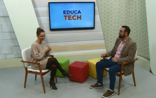 Na image, um homem e uma mulher conversam sobre pensamento educacional em um estúdio de TV