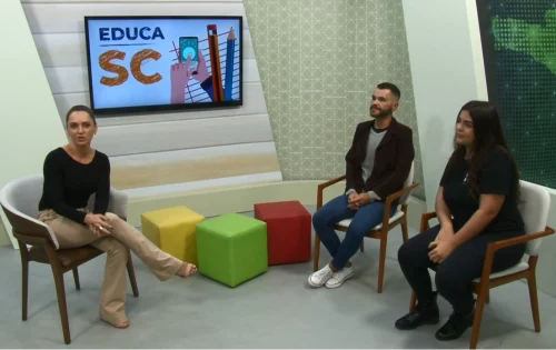 Na imagem, três pessoas conversam sobre o novo ensino médio em um estúdio de tv