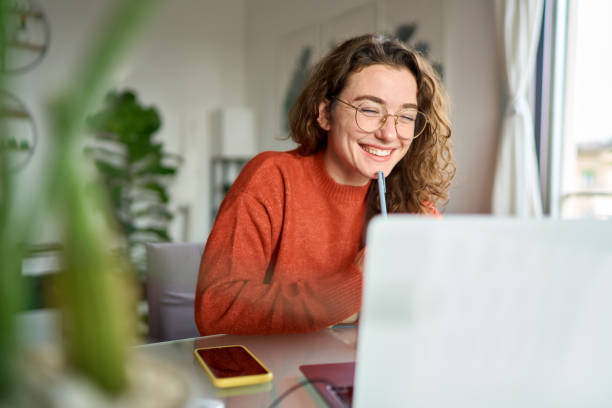 Imagem mostra estudante em frente ao computador sorrindo