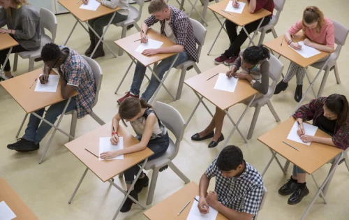 imagem mostra jovens sentados em sala de aula realizando prova