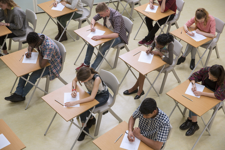 imagem mostra jovens sentados em sala de aula realizando prova